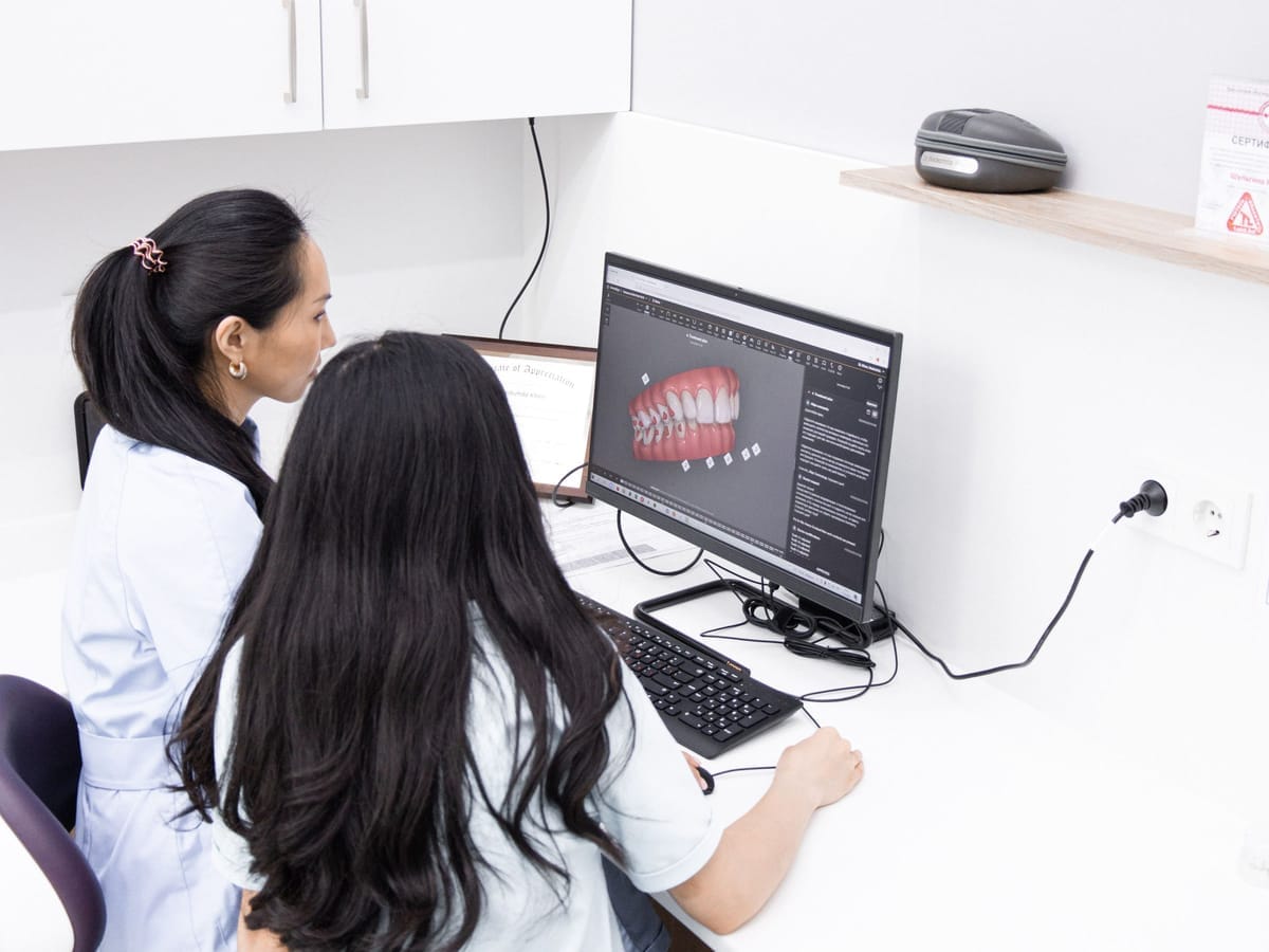 Two dental professionals reviewing images on a computer screen