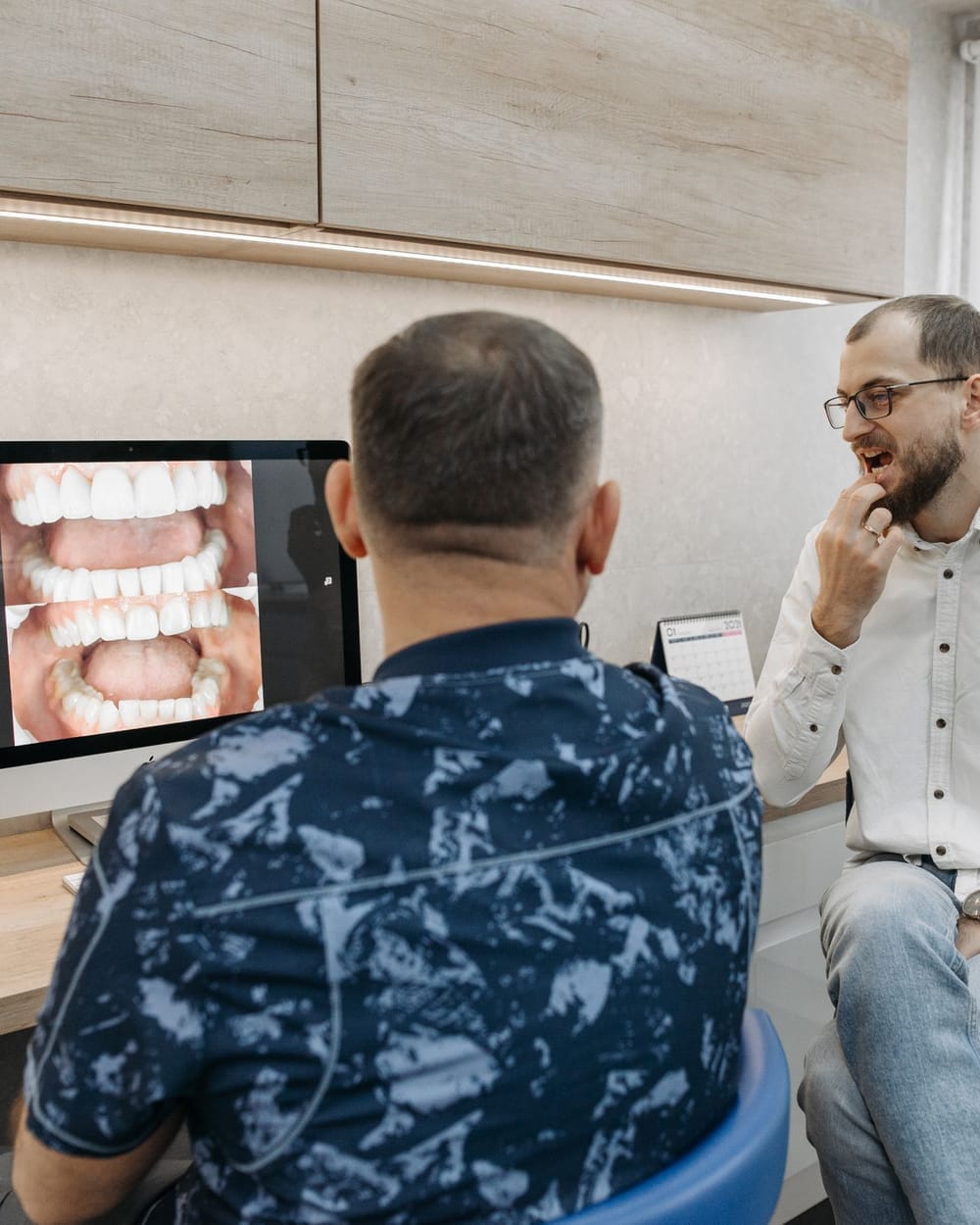 A dentist and a patient reviewing images together on a screen