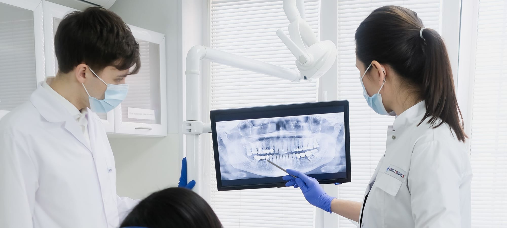 Two dentists reviewing a dental x-ray on a screen in a bright clinic