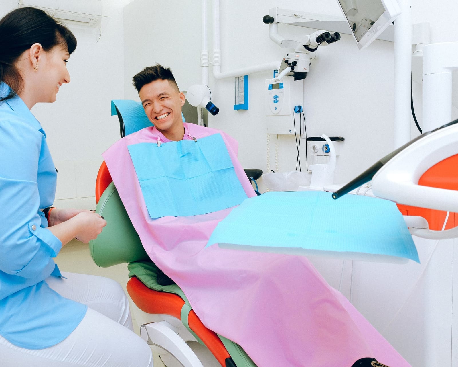 A dentist talking with a smiling patient in a dental chair
