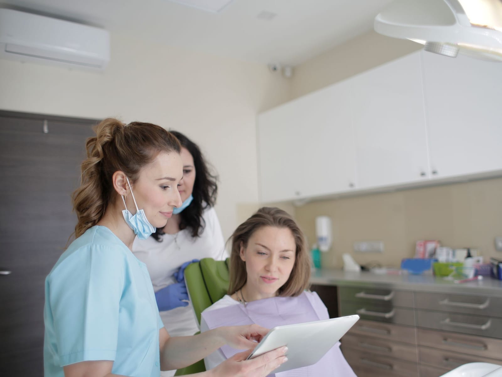 Two dental team members showing a patient something on a tablet